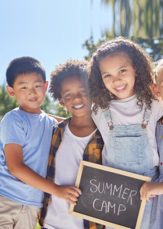 Shot of a group of friends holding a sign in a outside in a park